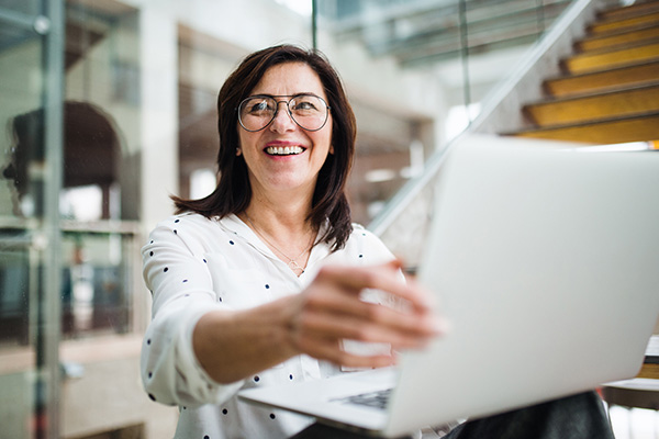 Woman smiling and holding a laptop