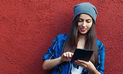 GenZ woman wearing a hat and using a tablet