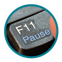 Finger pressing f11 pause key on a keyboard